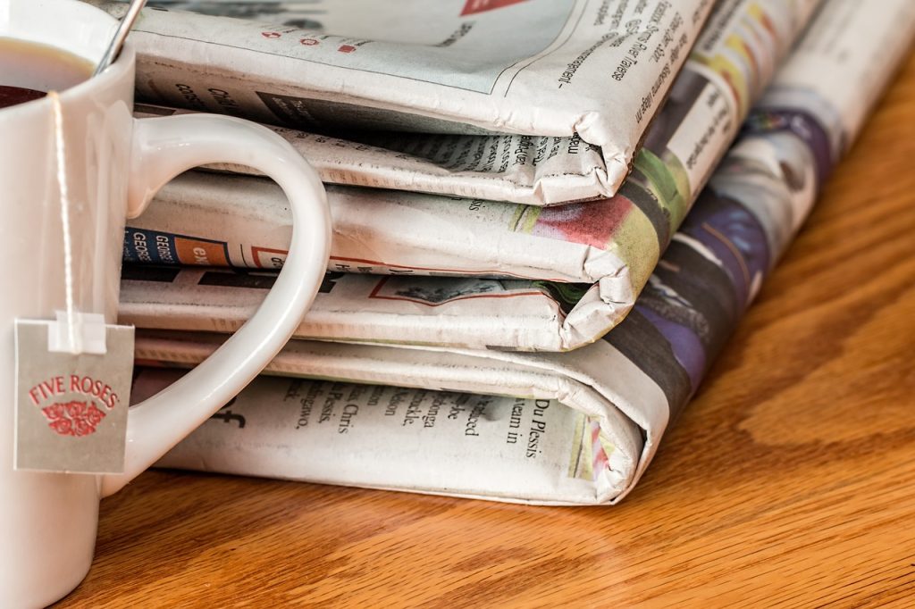 Mug of tea beside pile of newspapers