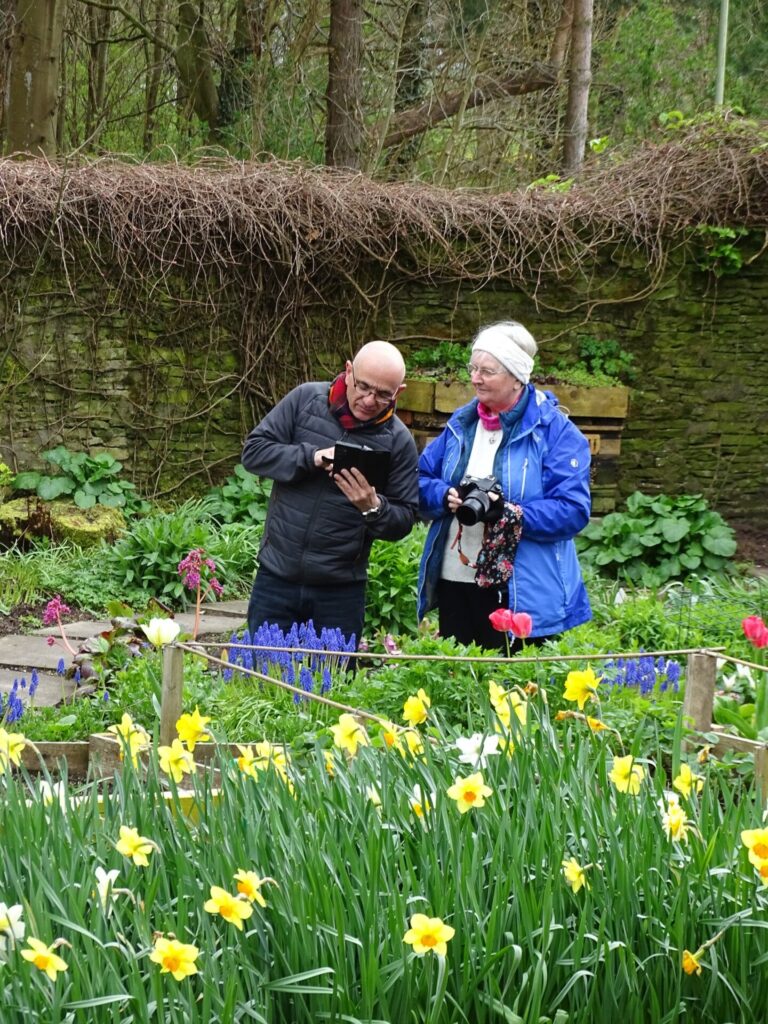 Two members of the photography group with cameras in a walled flower garden