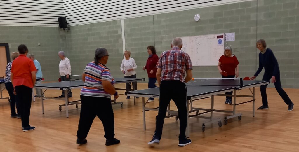 u3a table tennis group playing table tennis in gym hall